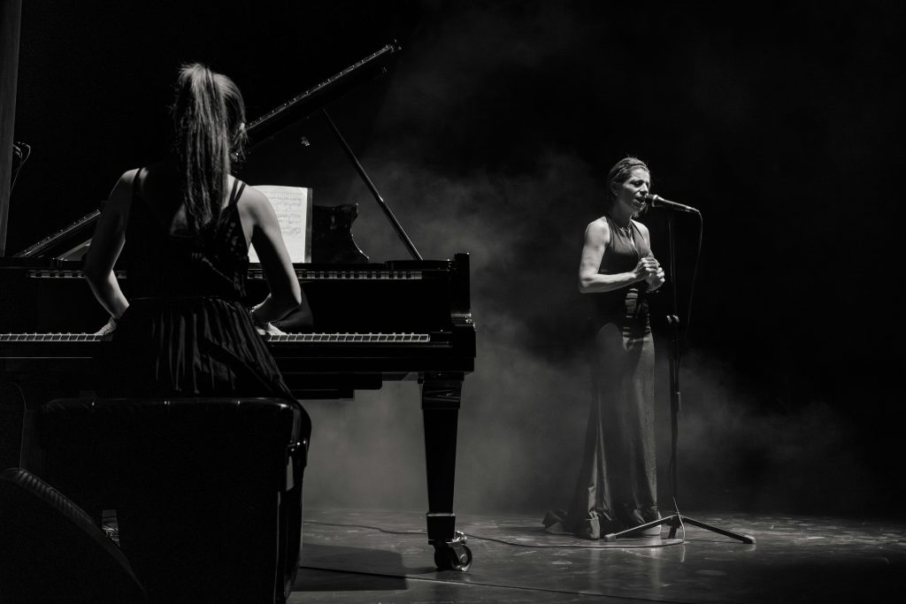 A captivating black and white image of a singer and pianist performing on stage.